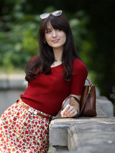 a lady wears a floral printed skirt with a red knitted top